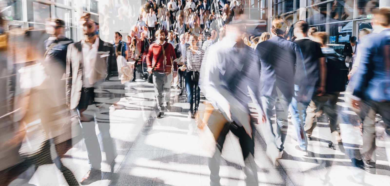 A busy station concourse or passageway filled with people walking in different directions, creating a blurred and dynamic image