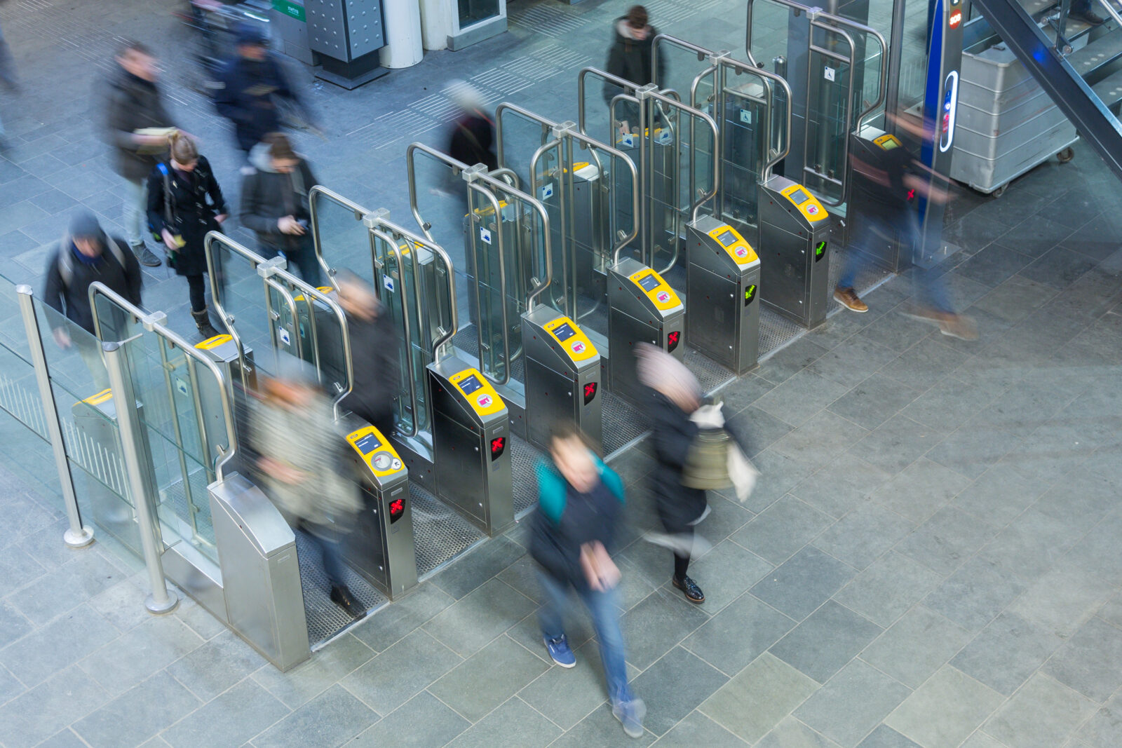 Passengers walk through the public transit gates in a station concourse and check in using a debit card or smartphone