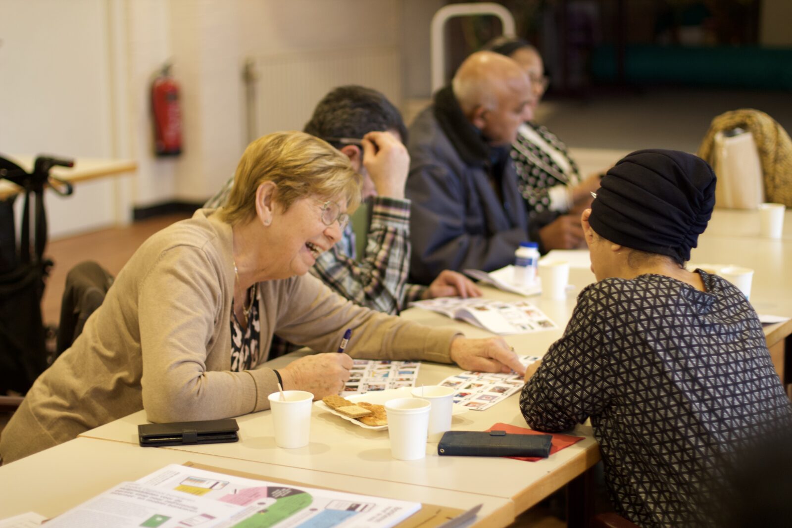 A group of people sits around a table at a community center and reviews documents and forms together while receiving personalized assistance with banking matters